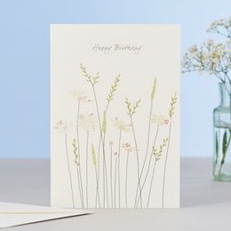 A birthday card featuring a simple, elegant design of delicate wildflowers against a light background. The card has the text "Happy Birthday" printed in a cursive font.