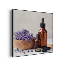 Lavender-infused beauty products including a square painting, essential oil bottles, and a wooden bowl filled with lavender flowers.