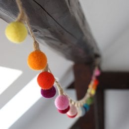 Colorful felt ball garland with assorted round felt balls in various bright colors including yellow, orange, red, pink, purple, and blue.