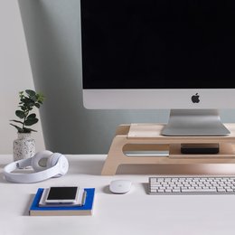 Wooden desktop stand for computer with curved design and storage space.