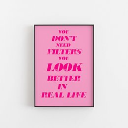 Wall art print with bold pink text that reads "You don't need filters, you look better in real life". The print has a simple, minimalist design with a vibrant pink background.