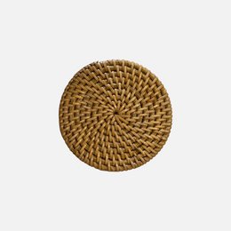 Round woven rattan coaster, natural brown color, intricate spiral pattern.