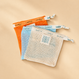Reusable mesh soap bag made of natural cotton, with a drawstring closure and a logo patch. The bag is designed to hold and store bar soaps, allowing them to dry between uses.