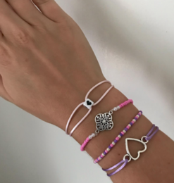  A set of bracelets featuring a mix of purple and pink beads, with a decorative metal charm.
