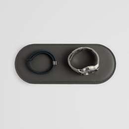 Stylish grey leather pad for small accessories, available in black, brown, and grey. Designed for organizing and storing small items.