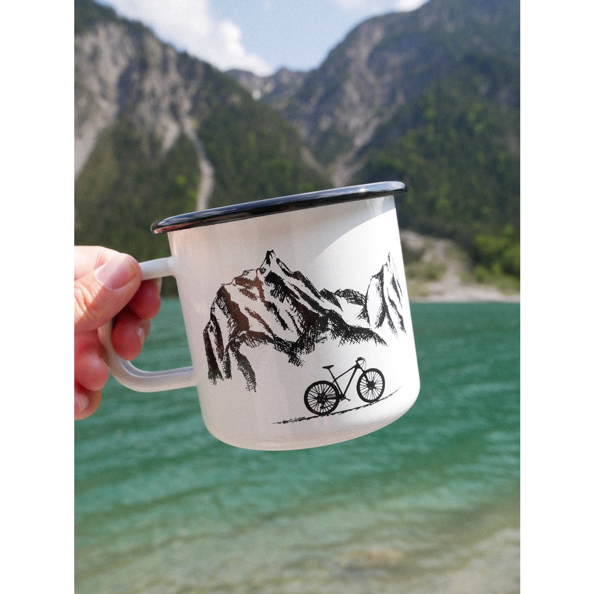 Taza esmaltada montañas y rueda.
