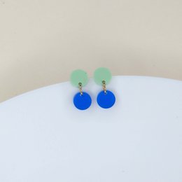 Dotty acrylic earrings in light green and deep blue, featuring a statement design with round blue pendants.