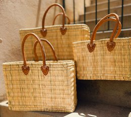  Set of 3 natural woven straw handbags with leather handles and accents.