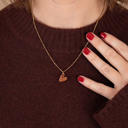 Copper heart-shaped charm pendant on a gold chain necklace.