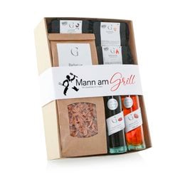 This gift set includes a variety of spice mixes and seasonings for grilling, including a rub, marinade, and spice blend. The set comes in a wooden crate with the "Mann am Grill" (Man at the Grill) branding.