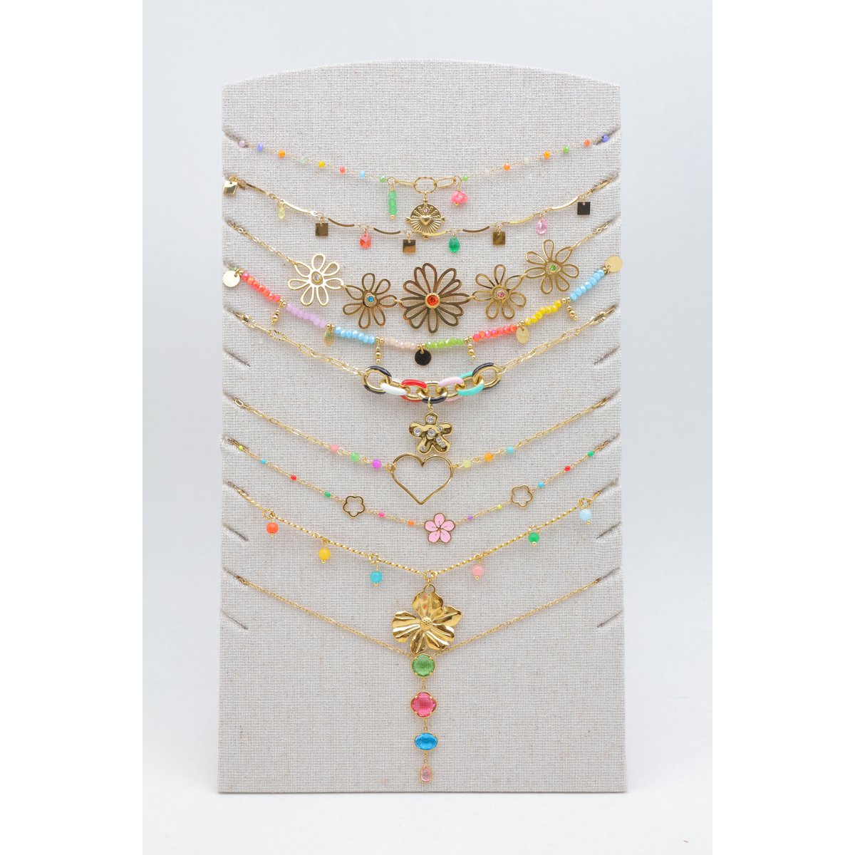Lot de 9 colliers multicolores assortis en acier inoxydable, présentés sur un support en tissu de lin avec pied de soutien à l'arrière. Présentoir et bijoux prêts à être exposés directement. L'ensemble est livré et protégé sous papier bulle