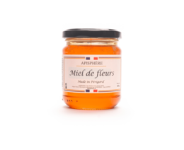 Honey-colored liquid in a glass jar labeled "Miel de Fleurs" (Flower Honey). The honey appears to be thick and viscous, with a rich, golden color.