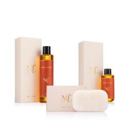 Luxury beauty gift set with amber glass bottles, cream soap bar, beige packaging, golden oil spray bottles, elegant skincare collection.