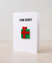 "Christmas greeting card with colorful Lego brick gift box design, red green festive present"