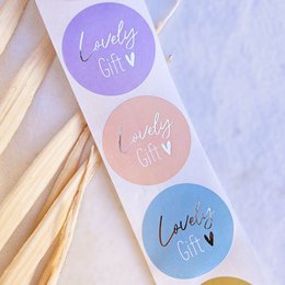 Colorful round stickers with the text "Lovely Gift" in various pastel shades. The stickers appear to be decorative or packaging elements, potentially for gifts or other products.