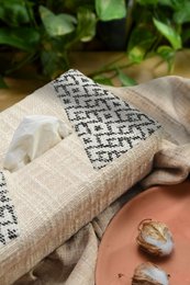 Handwoven tissue box, natural beige linen, geometric black pattern, rectangular shape, decorative home accessory.