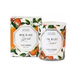 A tall, round orange blossom scented candle with a silver necklace charm inside.