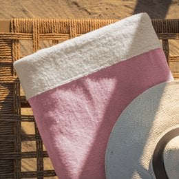 Large, soft, pink and white beach towel with a textured pattern, perfect for relaxing on the sand.