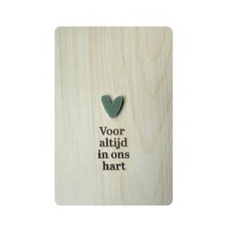  A wooden postcard with the text "Voor altijd in ons hart" (Forever in our hearts) and a heart-shaped embellishment. The postcard is displayed on a wooden shelf.