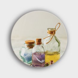 A round wall circle with various small glass bottles containing aromatic oils. The bottles are in different colors, including yellow, purple, and blue. The wall circle is a decorative piece for displaying essential oils or other small items.