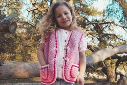 Cozy pink knitted bodywarmer with floral pattern, suitable for children aged 7-14 years old.