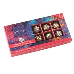 Organic date pralines in a red box, featuring dark chocolate-coated dates with white chocolate drizzle and sprinkles.