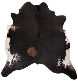 A large, rectangular cowhide rug in a dark brown and black color pattern, measuring approximately 180 x 160 cm.