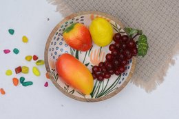 Decorative serving bowl with floral pattern, containing various fruits including oranges, lemons, and grapes.
