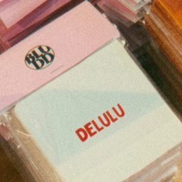 A green tile with the text "LET THEM SMELL A POOPIE" in bold pink letters. The tile appears to be a decorative or humorous home accessory.