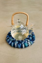 Blue-toned coaster with a glass teapot on top.