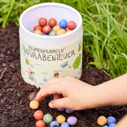 Colorful nature-themed tin filled with assorted marbles in various shapes and hues, perfect for an adventure-filled experience.