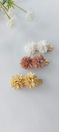 Colorful floral hair clips in various sizes and shades including white, pink, and yellow.