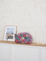 Colorful floral makeup clutch, vibrant multicolor flowers, green fabric pouch, cosmetic organizer bag.