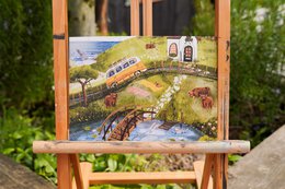 Wooden easel display, landscape illustration print, train bridge river scene, nature artwork, vintage style poster.