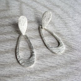 Silver teardrop-shaped stud earrings with a textured surface.