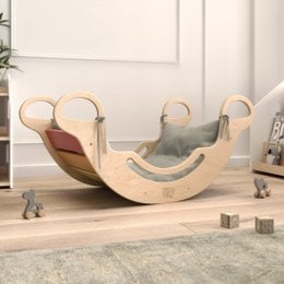 Wooden balance rocker with gray cushion and purple strap. Designed for children's play and development.
