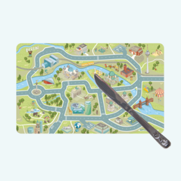 Rectangular wooden cutting board with a colorful map-like design featuring various food items and kitchen tools. The board is shown with a slice of toast or bread on it.