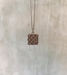 Silver pendant necklace with a square-shaped charm featuring a repeating heart pattern.