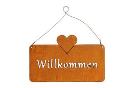 Rustic orange wooden sign with the German word "Willkommen" (Welcome) and a heart-shaped design. The sign is hanging on a wire.