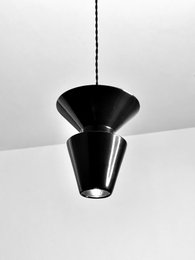 Black pendant light with a conical shape and a single light source.