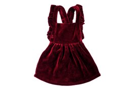 A burgundy-colored velvet baby dress with a pinafore-style design, featuring a high neckline, ruffled straps, and a flared skirt. The dress is available in sizes 68, 74, 80, 86, and 92.