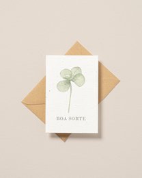 Plantable postcard with a pressed four-leaf clover design, representing good luck. Neutral-toned, minimalist design.