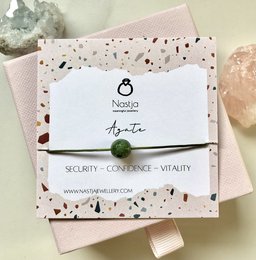Agate gemstone bracelet with a green pom-pom charm, featuring a modern, minimalist design. The bracelet is made of natural agate stones in various shades of gray, creating a unique and stylish accessory.