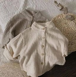 Cream-colored muslin shirt for kids, available in sizes 12-18M to 7-8Y. Features a button-up design and a relaxed, comfortable fit.