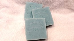 Handmade natural soap bars in a light green color. The bars have a simple, minimalist design with a circular logo imprint.