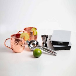 Copper Moscow Mule cocktail set with mugs, jigger, and lime. Includes essential tools for mixing and serving classic Moscow Mule drinks.