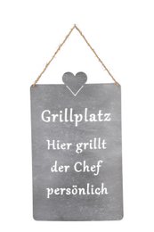 A rectangular gray slate sign with a heart shape and the text "Grillplatz - Hier grillt der Chef persönlich" (Grill area - The chef grills personally here).