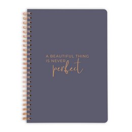 A dark gray spiral-bound notebook with the text "A beautiful thing is never perfect" printed in rose gold on the cover.