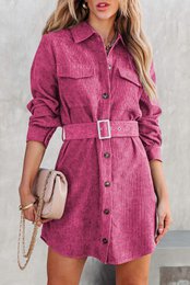 A vibrant pink corduroy dress with a belted waist, long sleeves, and a button-down front. The dress has a classic shirt dress silhouette and would be perfect for casual or semi-formal occasions.