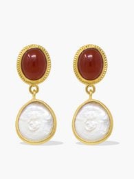 Gold-plated earrings with carnelian and pearl drops. Oval-shaped carnelian stones with white pearl accents. Elegant and sophisticated design suitable for formal or casual wear.